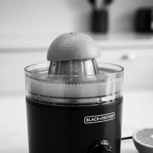 A close-up of a Black+Decker electric citrus juicer highlighting its auto-reversing cone and adjustable pulp control settings, ready to extract juice.