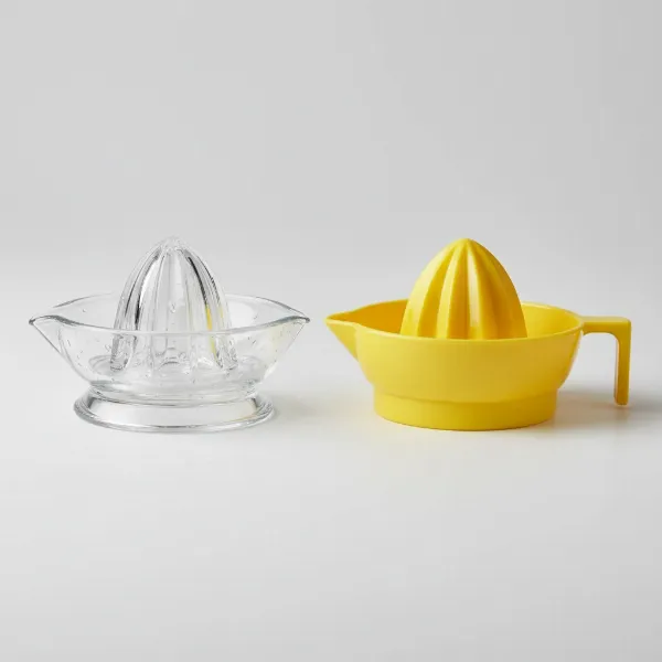 Side-by-side view of a translucent glass citrus reamer and a vibrant yellow plastic citrus reamer