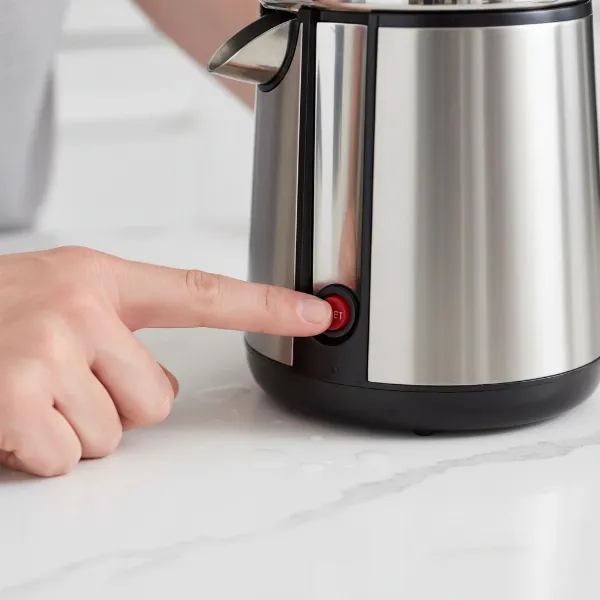 Person pressing the small reset button on the base of a citrus juicer to restore power.
